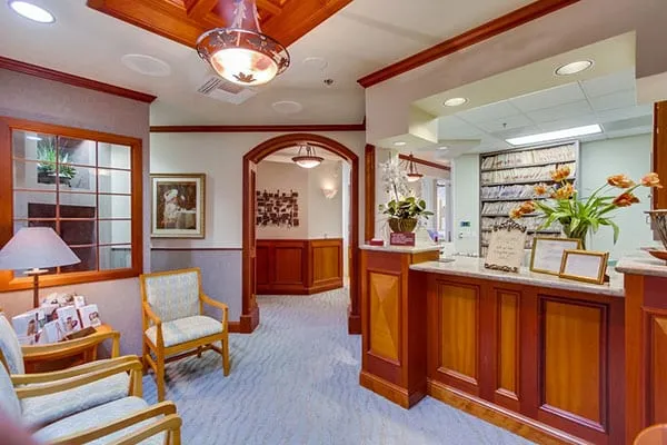 Our reception and waiting room, with cherry wood, upholstered chairs and an arched wood doorway